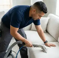 Professional upholstery cleaning technician using an extraction wand to deep-clean a fabric sofa, Duluth, MN.